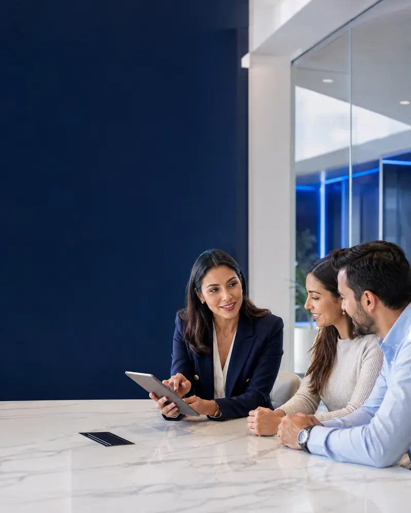 Asesora de Infiniti Group conversando con dos clientes en una oficina moderna